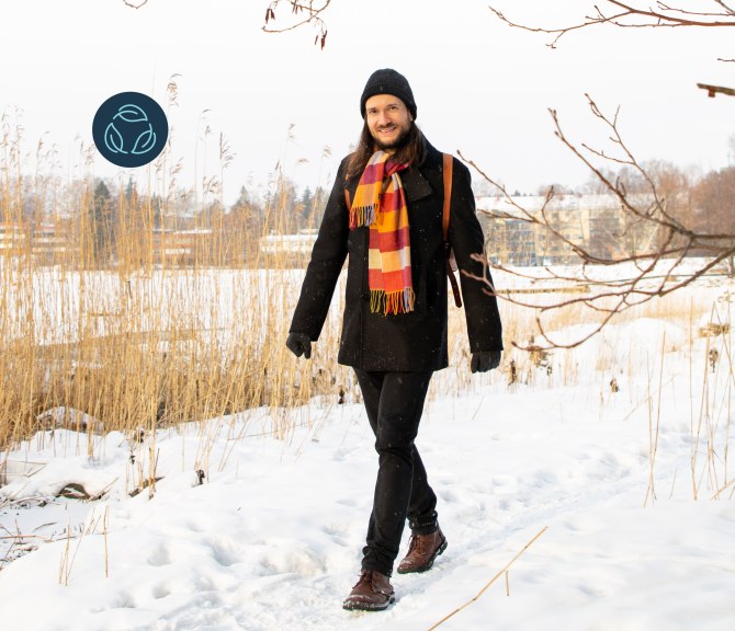 Jussi-Pekka Teini walks outdoors past a snowy bed of reeds.