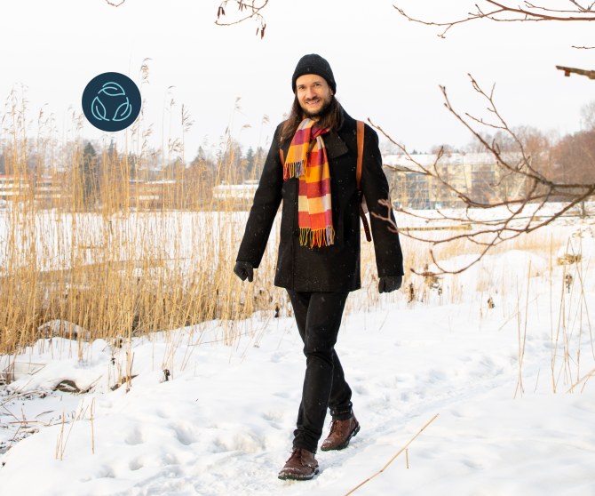 Jussi-Pekka Teini walks outdoors past a snowy bed of reeds.