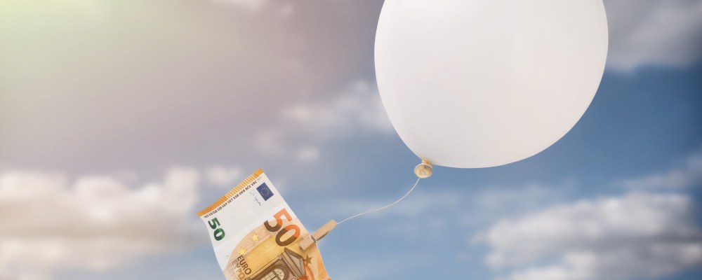 50 euron seteli roikkuu ilmapalloon kiinnitettynä taivaalla.