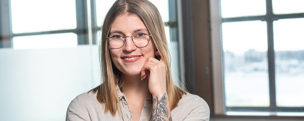 Karoliina Oksanen seisoo valoisassa tilassa ikkunan äärellä.