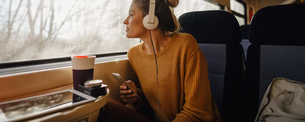 Tyttö istuu junassa ja katsoo ikkunasta ulos