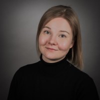 Kuva Senni Auvisesta. Tausta on tummanharmaa. Musta pitkähihainen paita, lyhyet vaaleat hiukset