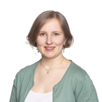 Nuori lyhyttukkainen nainen hymyilee aurinkoisesti vihreässä neuletakissa