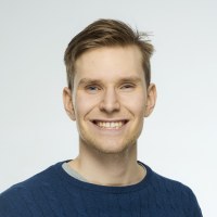 Kuva ehdokkaasta. Ruskeat hiukset, siniset silmät. Hymy, tummansininen neule.