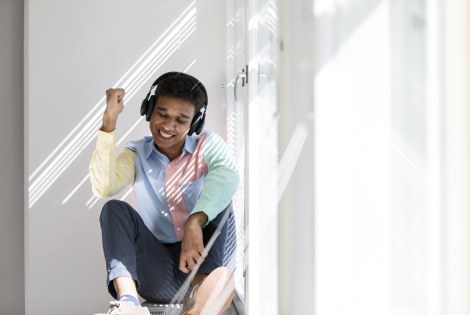 Henkilö istuu ikkunalaudalla kuulokkeet päässä ja tuulettaa